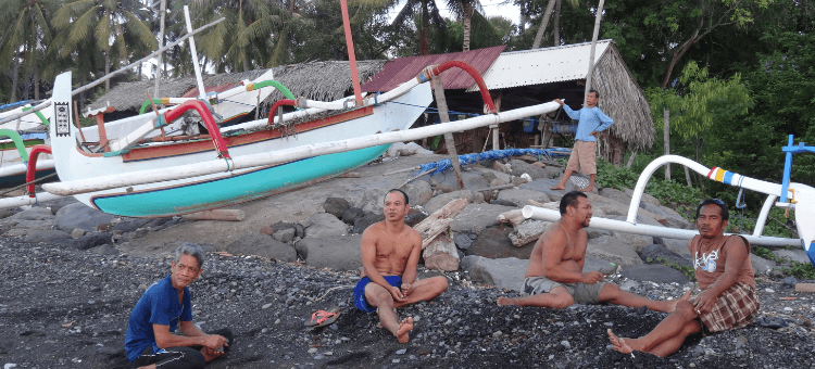 Der Fischer von Bali: Balinesische Fischer sitzen am Strand. Im Hintergrund ihre Fischerboote